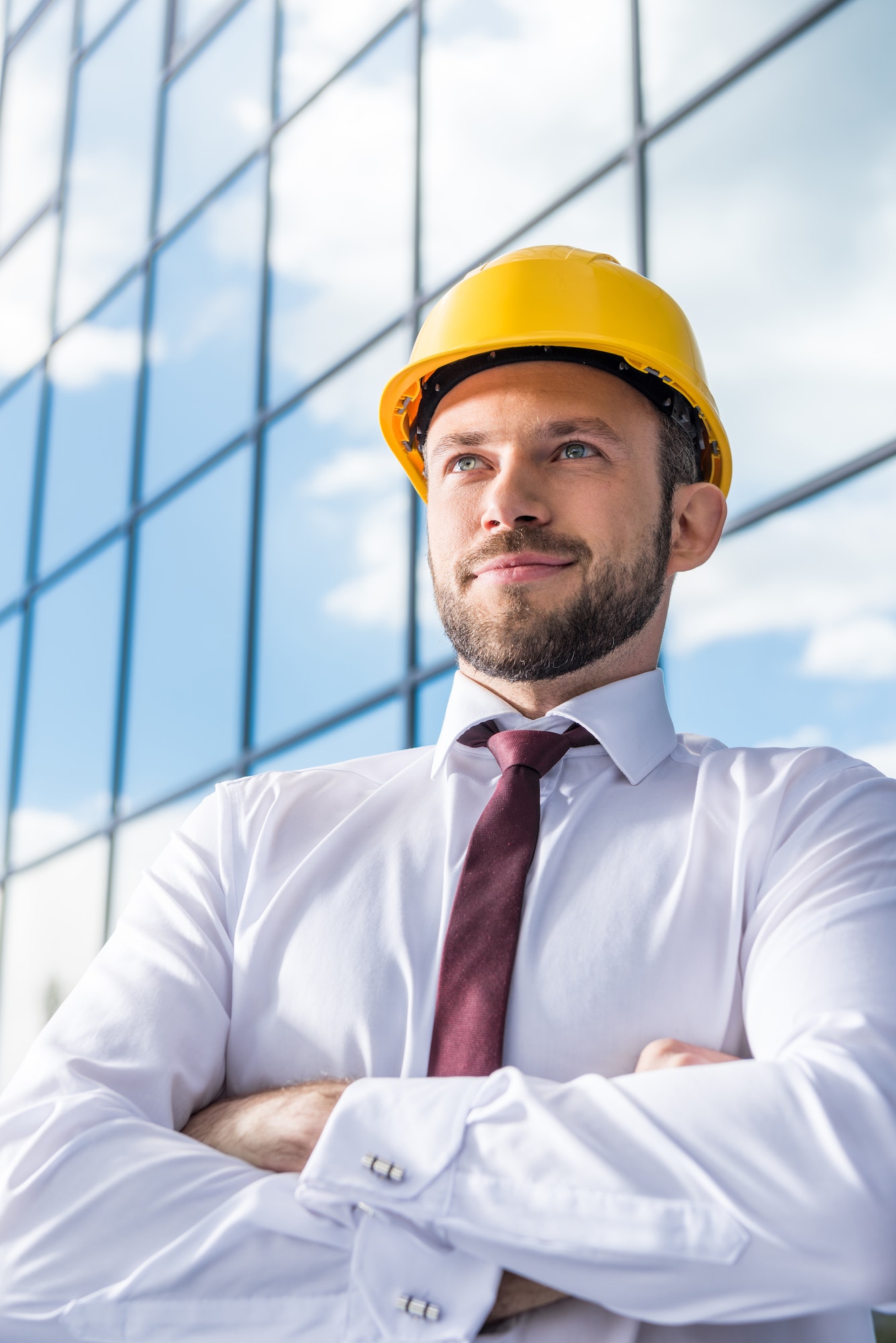 portrait of smiling professional architect in hard hat against building